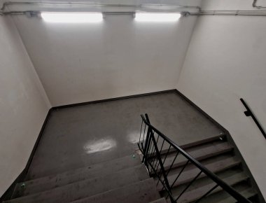 Sapının altında sarı ışıklı bir LED şerit var. Gizli lamba bir adamın elini gösteriyor. Merdivenin beton tarafı, istinat duvarları olan gece, koridor.