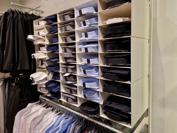 the wardrobe with shelves is clearly divided by color and type of clothing. shirts with collars in a palette of colors and t-shirts and hoodies for the customer to choose according to taste
