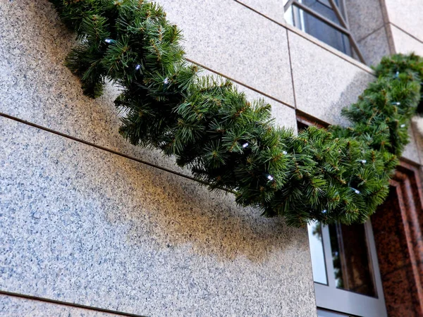 decoration of the house using suspended fir branches on the facade facing the street. a garland in wavy arcs lines the main street and the square, close up