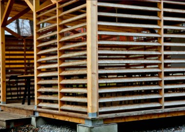 Parktaki pavyonun tahtalar ya da lomboz şeklinde kenarları var. Pergola havalıdır ve güneşten yanlardan korur. Şeffaf plastikten yapılmış pleksiglas bir çatısı var.