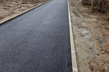 Beton kaldırımın betona dönüştürülmesi. Asfalt tabakasını döşeyip yuvarlanmadan önce sadece beton tabanı olan yol boşluğunda. Duvarcılık, duvarcılık, teknoloji, eğimli kenar