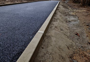 Beton kaldırımın betona dönüştürülmesi. Asfalt tabakasını döşeyip yuvarlanmadan önce sadece beton tabanı olan yol boşluğunda. Duvarcılık, duvarcılık, teknoloji, eğimli kenar