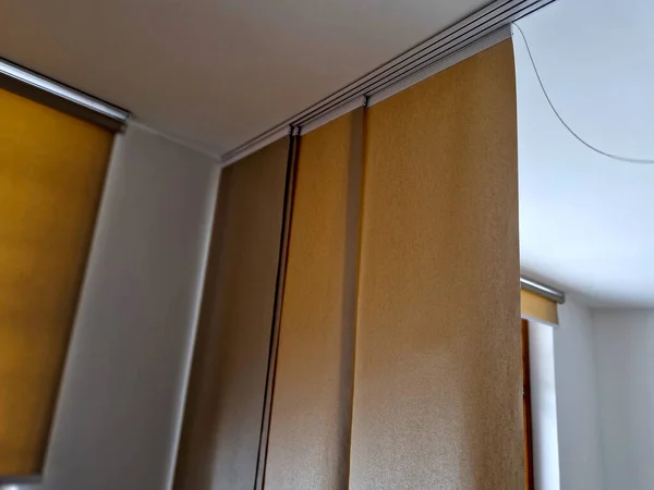 extendable hanging blind is a dividing partition made of textile beige blinds. home screen in the living room or dining room. rails and travel cable