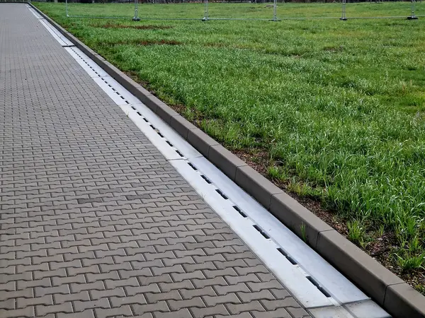 Slotted pipes drain rainwater and oil substances, drips from paved surfaces. concrete products at the curb interlocked paving tiles. sewage pipes hidden under the surface