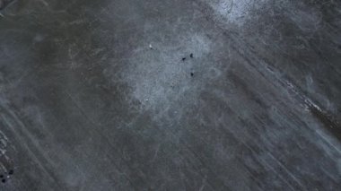 Su basmış tarla çok güzel bir buz pateni sahası, çiftçiye verdiği zararı saymazsak. Hokey oynamak ya da büyük bir su birikintisinde kaymak yukarıdan çekilen çekimlerle belgelenir. Köyün eğlenceli çocukları. yeşil