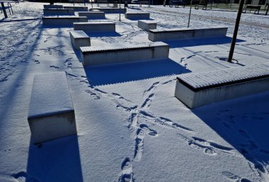 Beton beyaz bank bloğu ve parkta dalga şekli koyu renkli bir meydanda, temiz beton yüzey gri kahverengi beyaz yayalar ve kaykay parkında gençler, gençler, ayak izleri için dinlenme alanı.