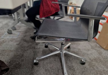 Ofiste unutulmuş bir sırt çantası. Gri halı. Toplantı odasında ağ yüzeyi olan paslanmaz çelik iğne. Tekerlekli. gümüş rengi.