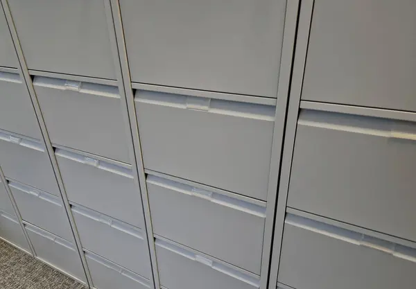 index card alphabetically arranged database of documents in metal pull-out drawers with a key lock. gray tin containers at the doctor's office