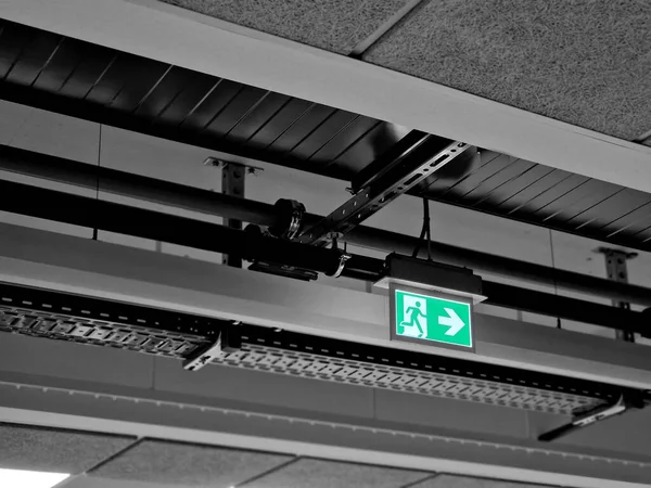in the factory, transparent signs with backlight and an arrow to the escape exit from the building hang from the ceiling. open door and stick figure. connected to an independent electrical circuit