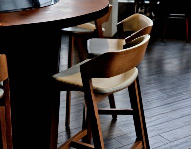 Bar mutfak tezgahı. Deri döşemeleri olan güzel ahşap sandalye. Kavisli yuvarlak masada kahverengi renkli. Bilgisayarla çalışmak için ideal