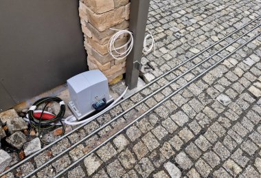 Bahçeye açılan kapı. Çalışan bir dişlisi var ve bir dişli tekerlek geri çekilir ve uzaktan kumandadaki talimatlara göre kapı yaprağını genişletir.