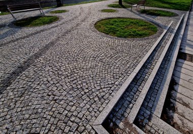 Basamaklar çiçek tarlasının ortasındaki küçük dairesel bir çimenliğe götürür. Kırmızı tropikal ağaçtan yapılmış eğimli bir bankta oturuyordu. Toprağın yüzeyine otomatik fıskiye hortumları, yılan, üst görünüm