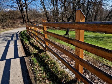 Kırsal çiftlik tarzı ahşap çitler. Direğin direkleri yerden çürümesin diye metal çivilerin üzerinde. Tepesi eğimli ve su girişine karşı metal bir çatı ile kaplı.