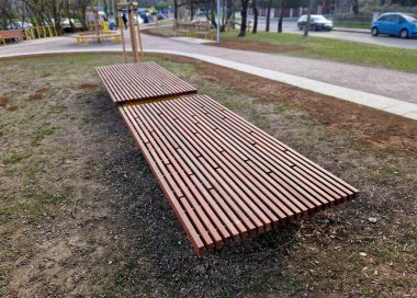 Parka bakan yükseltilmiş terasın kenarında ahşap panelli ve dikdörtgen banklı uzun bir saksı var. Şehrin cadde ve meydanındaki gezinti alanlarından biri.