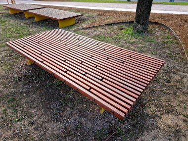 Parka bakan yükseltilmiş terasın kenarında ahşap panelli ve dikdörtgen banklı uzun bir saksı var. Şehrin cadde ve meydanındaki gezinti alanlarından biri.