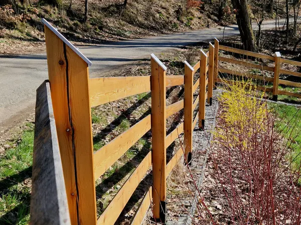 Kırsal çiftlik tarzı ahşap çitler. Direğin direkleri yerden çürümesin diye metal çivilerin üzerinde. Tepesi eğimli ve su girişine karşı metal bir çatı ile kaplı.