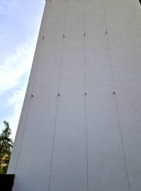 Evin duvarına bağlı paslanmaz çelik kablolardan yapılmış metal trellisler büyür ve sarmaşığı sarar. Sütun tüneli. Kıskaç, tutuş, tutuş, tutuş, bükülme, sürünme detayı