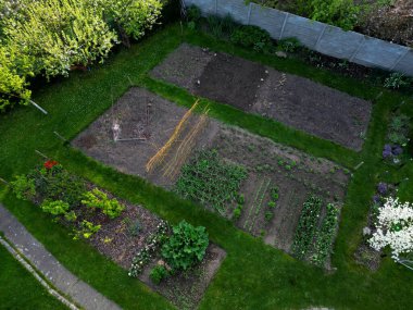 Bahçede sebze bahçesi ve futbol golleri olan bir elbise rafı. bahar çiçekli çalılar, tarlalar ve çatı