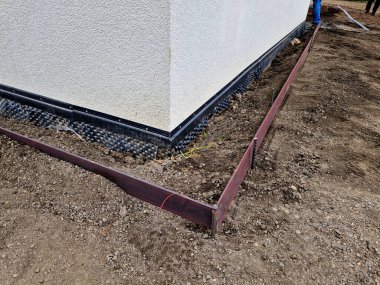 Evin etrafında çakıl ve çakıl taşlarından oluşan bir oluk oluşturmak her zaman gereklidir. Suyu emmeye ve evin duvarlarını havalandırmaya yarıyor. Kaldırım çelik levhaların montajı. zar folyosu