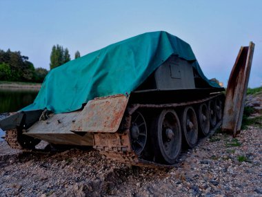  Tank, nehir yatağını geçtikten sonra kumlu bir sahilde çelik bir sütuna çarptı. Anti-dron brandası ve tekerleklerle gizlenmiş bir istila gücü.