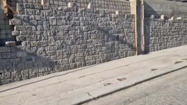 Tuğlacılar evi kumtaşı taşlarıyla kaplıyor. Taşları çimentoya bağlıyorlar. Kaplamanın arkasında düğmeli ve polistirenli izolasyon var..