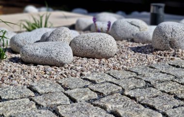 Süslü çiçek tarhı. Gri granitten yapılmış taşlar, şehir bahçesinde saman taşları, çayır, süs otları, havuz kenarında teras, çakıl taşı, mor, beyaz...