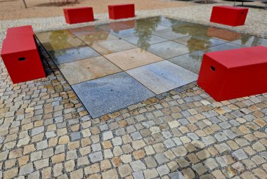 Kaldırımda kaldırıma yığılmış kare granit kaldırım taşları, sırayla püskürtülmüş su püskürtüleri. Su özellikleri doğrudan park sırasındaki kaldırımlı meydandan ortaya çıkıyor. ıslak kiremitler tahta kaldırım, kum, çakıl