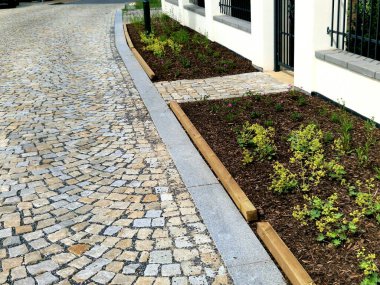 siyah örgülü beyaz çit. Çiçek tarhının etrafı arabaların tekerlekleriyle çevrili.