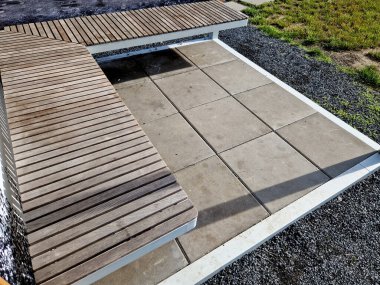 Tente ile kaplı kirişlerden yapılmış ve çelik kablo yapısına reklam afişi olarak göz dirsekleriyle bağlanmış bir pergola. Sarı ve bej levhaların gölgelendirme kumaşı kamp tezgahını ve masayı korur.