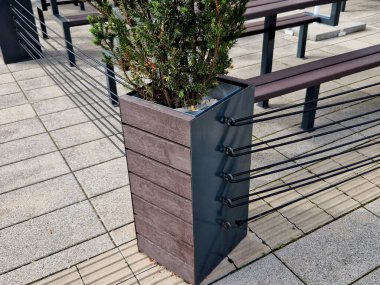 in the front garden of the restaurant, the flower pots are connected by several ropes and provide a fence for seating in the outdoor cafe. a flowerpot covered with a reed mat clipart