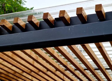 Duvarlarının kenarlarında çıtası olan metal pergola yapısından yapılmış modern pazar standı. Otobüs durağındaki sigara içilen barınakların çizgili görüntüsü.