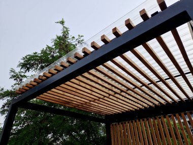 Duvarlarının kenarlarında çıtası olan metal pergola yapısından yapılmış modern pazar standı. Otobüs durağındaki sigara içilen barınakların çizgili görüntüsü.