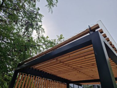 Duvarlarının kenarlarında çıtası olan metal pergola yapısından yapılmış modern pazar standı. Otobüs durağındaki sigara içilen barınakların çizgili görüntüsü.