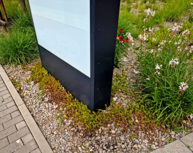 Katı gri desenli hafif afiş. Çiçek tarhında reklam amaçlı bir ilan var..