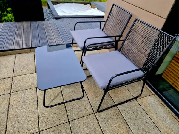 Kafe terasında ahşap bir masa ve teneke kutuda bir çiçek. Soğuğa yakalanan ziyaretçileri örtmek için arkada battaniyeler olmalı. Sonbahar terasında kahve, kasaba meydanı.