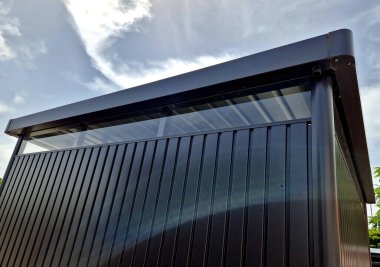 Çatının altındaki şeritte çok yüksek pencereleri olan gri amaçlı bina. Metal kaplamanın neredeyse hiç bakıma ihtiyacı yok.