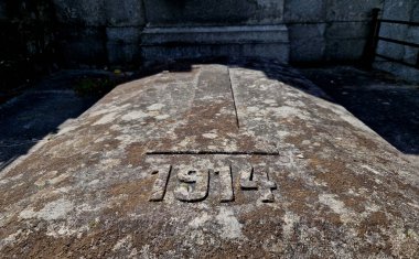 Taş mezar taşları. Savaşın başlangıcında Sırbistan ya da Rusya 'da ölen bir çocuğun anısına 1914 yılına kazınmış bir yazı. Bir savaş oyunu için arka plan olarak liken kaplı bir Alman mezarı