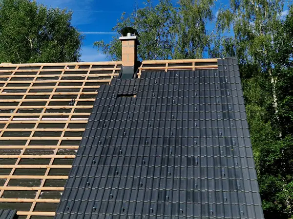 stock image construction site with several roofs in progress. Roofs with vapor-permeable foil. roof tiles are placed on the roof. concrete chimney passes through. approval quality control. view from above