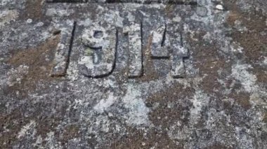 Taş mezar taşları. Savaşın başlangıcında Sırbistan ya da Rusya 'da ölen bir çocuğun anısına 1914 yılına kazınmış bir yazı. Bir savaş oyunu için arka plan olarak liken kaplı bir Alman mezarı