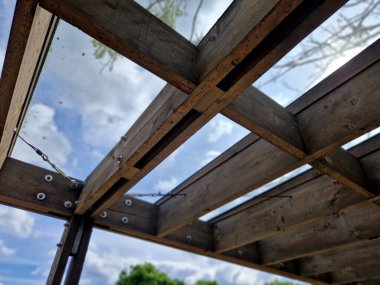 Pergola 'nın kahverengi yapışkan ahşap yapısı düz silindirik beyaz sütunlar tarafından desteklenmektedir. Çatı kiremitlerden, cam camlardan, ağaç tepesinden, kvh, akçaağaç ağacından yapılmıştır.