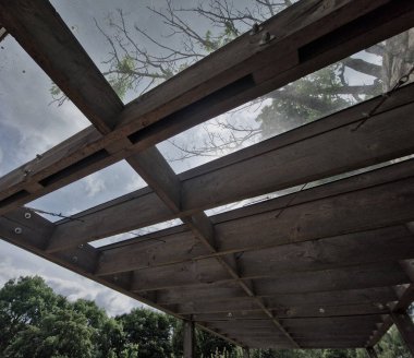 Pergola 'nın kahverengi yapışkan ahşap yapısı düz silindirik beyaz sütunlar tarafından desteklenmektedir. Çatı kiremitlerden, cam camlardan, ağaç tepesinden, kvh, akçaağaç ağacından yapılmıştır.