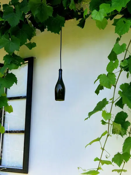 Stock image a cottage building from the 19th century with open windows. a champagne bottle on a cable hangs down like a stylish wine world on a stone-tiled terrace