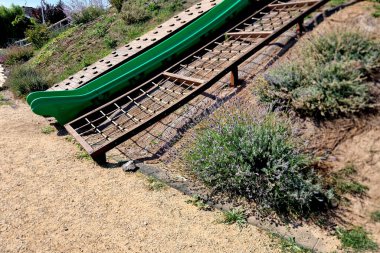 Ağın tepesine tırman ve fiberglastan yapılmış kaydırağın altına in. eğimli bir düzlemde duvara tırmanmak, lavanta, lavanta angustifolia