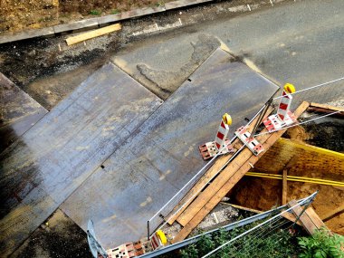 Kavşaktan geçen kazı alanı ve yol kesişen plakalarla kaplı. Araçlar tamir alanının üzerinden dikkatle geçebilir. yukarıdan dikey görünüm