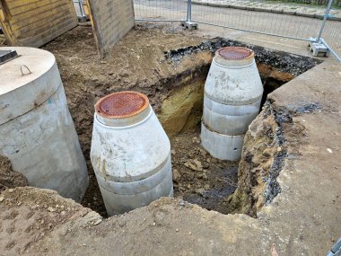 sump and control shafts of the sewage channel leading below the surface to the wastewater treatment plant. cylinder-shaped concrete rings with a lid clipart