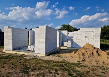 Bir aile evinin inşaat alanının manzarası. Silo sıva çimento karışımı. Çatı kirişi. Kirişler, binanın içinde yalıtımlı tuğla paletleri, geliştirme, finans, mikser