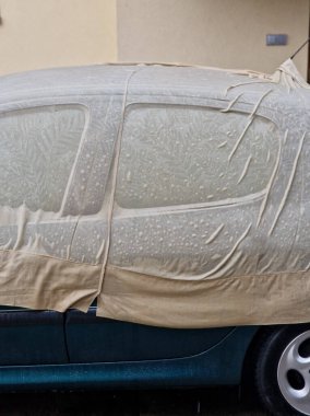 Şehvetli ıslak kumaş arabanın metal levhalarının kıvrımlarına sarılıyor. Araba toplantısı için erotik bayan ıslak gömlek. Örtü, boyayı güneşten korumak için..