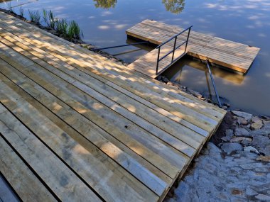 Gemileri demirlemek için yüzen bir iskele menteşeli metal çubuklarla sabitlenir. Ahşap merdivenler nehirdeki suyu gözlemlemek için kullanılır, Iris.