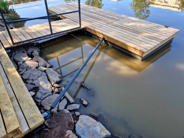 Gemileri demirlemek için yüzen bir iskele menteşeli metal çubuklarla sabitlenir. Ahşap merdivenler nehirdeki suyu gözlemlemek için kullanılır, Iris.