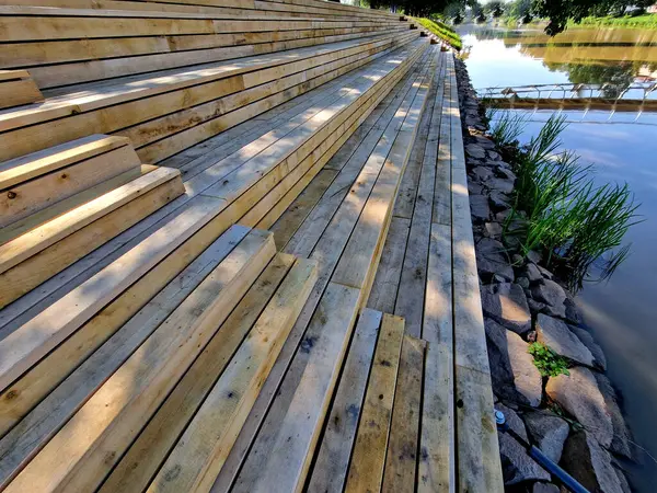 stock image a floating jetty for mooring ships is fixed with metal rods on hinges. wooden stairs are benches for observing the water on the river, iris